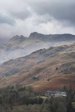 Beautiful Winter sunrise landscape view from Loughrigg Fell across the countryside towards Langdale Pikes and Pike O'Blisco in the Lake District