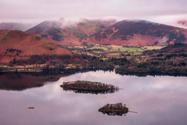 Beautiful Winter sunrise landscape image of view from Walla Crag in Lake District towards distant mountains with low cloud