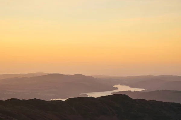 Beautiful Winter dawn landscape view from Red Screes in Lake District looking South towards Windermere with colorful vibrant sky
