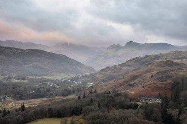 Beautiful Winter sunrise landscape view from Loughrigg Fell across the countryside towards Langdale Pikes and Pike O'Blisco in the Lake District