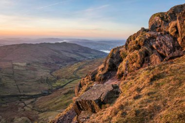 Beautiful Winter dawn landscape view from Red Screes in Lake District looking South towards Windermere with colorful vibrant sky