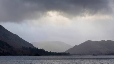 Beautiful Winter sunrise landscape over Ullwater in English Lake District with mist over lake giving a moody dramatic feel