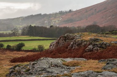Stunning Winter sunset golden hour landscape image of view from Wast Water over countryside in Lake District towards the Western district