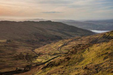 Beautiful Winter dawn landscape view from Red Screes in Lake District looking South towards Windermere with colorful vibrant sky