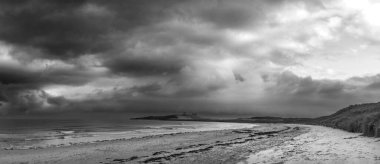 Beautiful unusual  black and white moody Winter landscape of snow on Embleton Bay beach in Northumberland England clipart