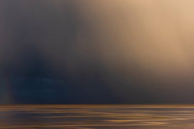 Okyanus manzarası üzerinde çarpıcı, fırtınalı gökyüzü ve uzak yağmur yağışı.