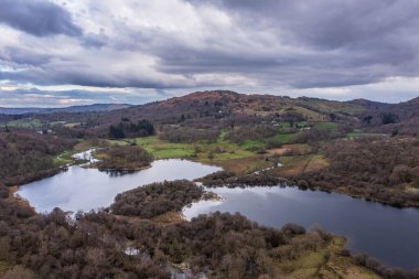 Beautiful aerial drone landscape image over River Brathay near Elterwater in Lake District with Langdale Pikes in distance clipart