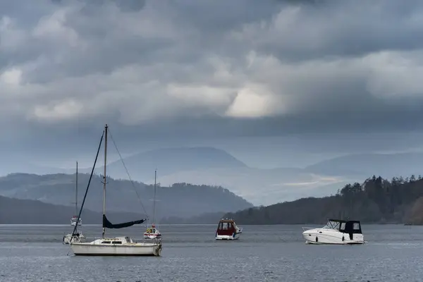 带山地背景的春日下午湖畔温得米尔湖上休憩船的景观图像 图库图片