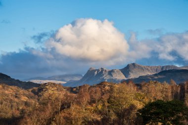 Stunning Spring landscape image in Lake District looking towards Langdale Pikes during colorful sunset clipart