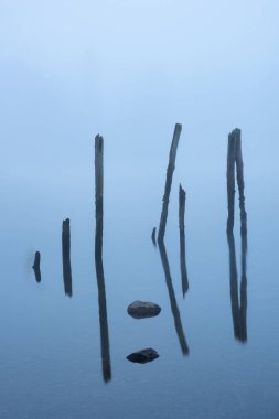 Sanatsal güzel sanatlar Derwentwater 'daki ahşap direklerin sonbahar sisli manzarası