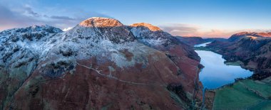 Stunning aerial drone landscape in Autumn Winter of snowcapped mountains around Buttermere in Lake District at sunrise clipart