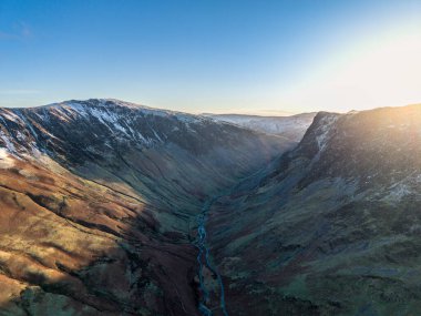 Stunning aerial drone landscape in Autumn Winter of snowcapped mountains around Buttermere in Lake District at sunrise clipart