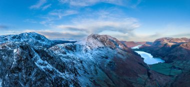 Stunning aerial drone landscape in Autumn Winter of snowcapped mountains around Buttermere in Lake District at sunrise clipart