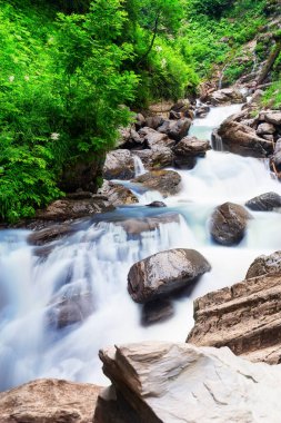 Dağ kayalıklarında şelale şelalesi. Bir dağ şelalesi kayaların üzerinden akar. Derin yağmur ormanı şelale manzarası.