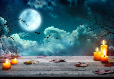 Ürkütücü Cadılar Bayramı balkabakları, Jack O 'Lantern, şeytani bir yüzü ve gözleri olan, sisli bir arka planı ve dolunayı olan tahta bir masa. Kara sisli arka planı olan Cadılar Bayramı Balkabağı.