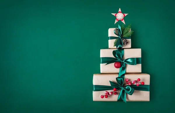 クリスマスツリーとクリスマススターの形をした緑色の背景にある3つのギフトボックス ホリデーバック ストック画像
