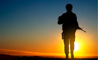 Silhouette of a walking soldier against the sunset. Armed forces concept. EPS10 vector