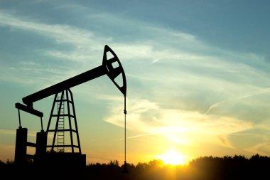 Gün batımına karşı petrol kulesi silueti. Petrol endüstrisi konsepti