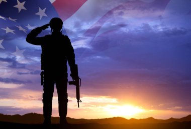 Gün batımına karşı Amerikan bayrağı taşıyan bir askerin silueti. Gaziler Günü. Hizmet Edenleri Onurlandırmak