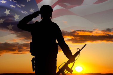 Gün batımına karşı Amerikan bayrağı taşıyan asker silueti. Gaziler Günü, Anma Günü, Bağımsızlık Günü konsepti