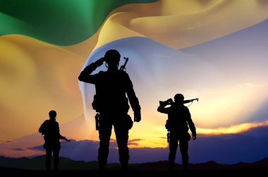 Gün batımına karşı Gabon bayrağı taşıyan bir askerin siluetleri. Ulusal Tatil Konsepti