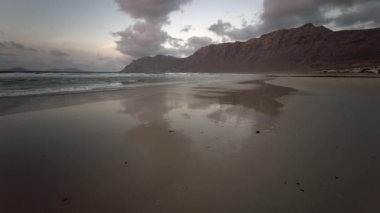 Famara Sahili 'nde güzel bir gün batımı. Lanzarote Kanarya Adaları Caleta de Famara, Famara Sahili Rüzgar sörfü ve akşam güneşinde sörf plajı