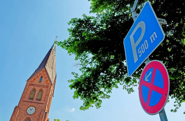 Evangelical Lutheran Church and parking sign - The neo-gothic Warnemunde Church tower rises above the Baltic coastal town of Rostock, Germany