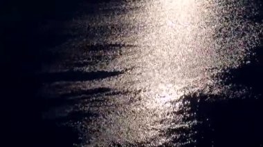 Deniz, parlak, aydınlık su ay ışığıyla parıldıyor. Derin mavi deniz suyu, güneş ışıldıyor. Bokeh etkisi, suda ışık yanıp sönüyor.
