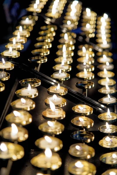 Votive candle rack or prayer candle rack with rows of flickering lit candles in Worcester Cathedral, England, United Kingdom. Photo taken on 28th of January 2023