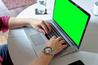 Genç profesyonel bir adam yeşil ekranlı dizüstü bilgisayar kullanıyor. Moda saati takıyor. Evden çalışma - Londra, Birleşik Krallık, 1 Haziran 2019