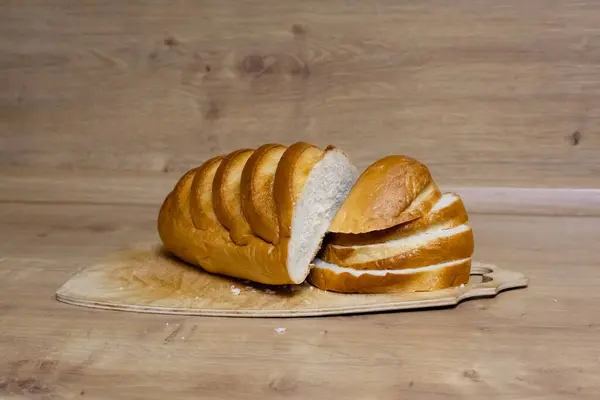 Tahta kesme tahtasındaki altın hamurlu taze beyaz ekmek..