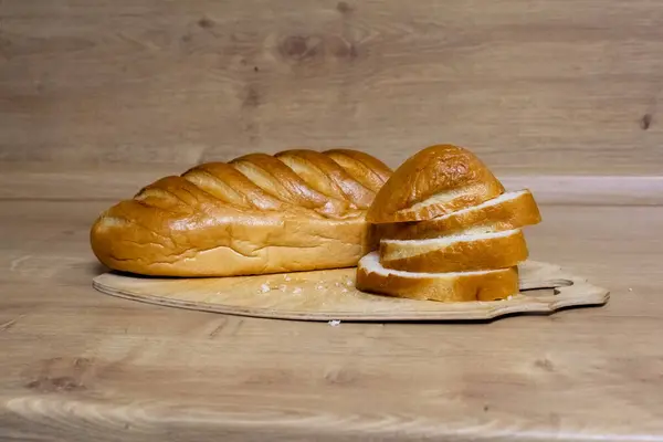 Tahta kesme tahtasındaki altın hamurlu taze beyaz ekmek..