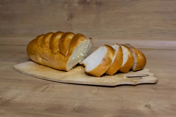Tahta kesme tahtasındaki altın hamurlu taze beyaz ekmek..