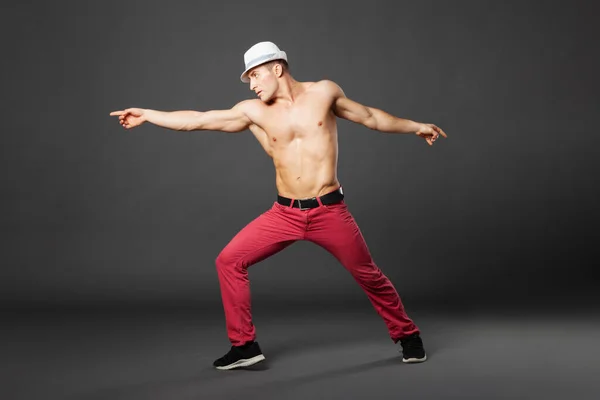 Young professional dancer dancing in studio isolated on gray background.