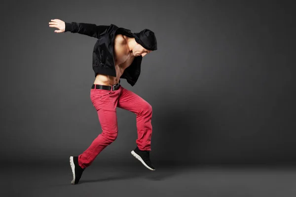 Young male professional dancer dancing in studio isolated on gray backhround.