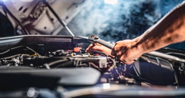 Auto mechanic working on car engine in mechanics garage. Repair service. authentic close-up shot - selective focus with motion blur