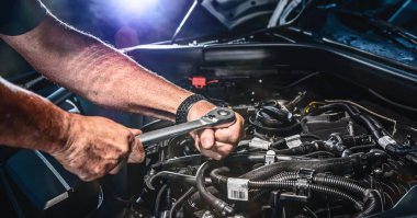 Auto mechanic working on car engine in mechanics garage. Repair service. authentic close-up shot - selective focus with motion blur