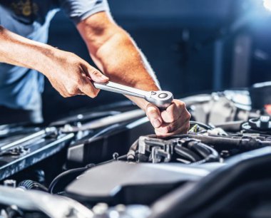 Auto mechanic working on car engine in mechanics garage. Repair service. authentic close-up shot - selective focus with motion blur