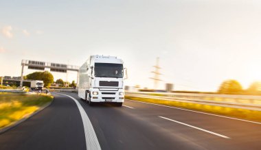 Yarı kamyonlar kargo ve paket teslimatı otoyolda gidiyor. Beyaz minibüs sabahın erken saatlerinde mal teslim eder. 