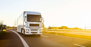 Kargo kamyonu ve kargo karavanı bir otoyolda gidiyor. Beyaz Kamyon sabahın erken saatlerinde mal teslim ediyor. Çok düşük açılı bir araç. Yakın çekim sırasında..