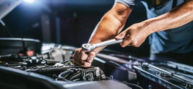 Auto mechanic working on car engine in mechanics garage. Repair service. authentic close-up shot - selective focus with motion blur clipart