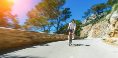 Yetişkin bir adam bisikletiyle Akdeniz 'de tepeye tırmanıyor Mallorca Balearic Adası' ndaki kıyı yolu.