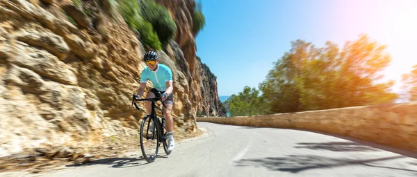 Man Adult on a racing bike climbing the hill at mediterranean sea landscape coastal road on mallorca balearic island