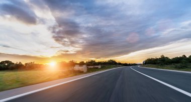 Güneşli yaz gününde kırsal kesimde asfalt yol manzarası.