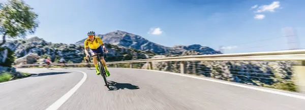 地中海の風景沿いの山道で丘を登るレーシングバイクの成熟した大人 モールカルロ山脈 ロイヤリティフリーのストック画像