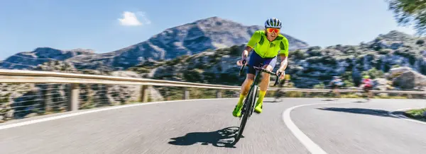 地中海の風景沿いの山道で丘を登るレーシングバイクの成熟した大人 モールカルロ山脈 ストックフォト