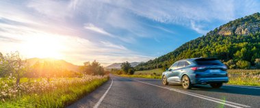 Günbatımında İspanya Dağları 'nda kiralık bir araba. Geniş açılı panorama çekimi