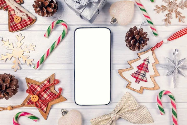 スマートフォンは アプリのプレゼンテーションのための白い木のテーブルの上に素朴なクリスマスの装飾でモックアップ 上からの眺め — ストック写真