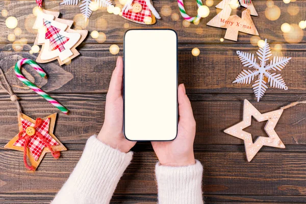 お祝いの木の近くに空の白い画面のモックアップ付き携帯電話を保持している女性を閉じます クリスマスを祝います 顧客ショッピングオンライン ギフトを購入 ガジェットのアプリを閲覧 — ストック写真