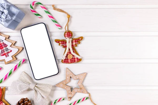 スマートフォンは アプリのプレゼンテーションのための白い木のテーブルの上に素朴なクリスマスの装飾でモックアップ 上からの眺め — ストック写真